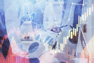 Double exposure of chart with businessman typing on computer in office on background. Concept of hard work.