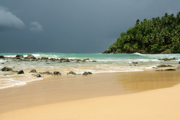 Beach in Mirissa, Sri Lanka: Turquois water, fine sand, waves for surfing, scattered with beautiful rocks and lined with coconut palms. Paradise!