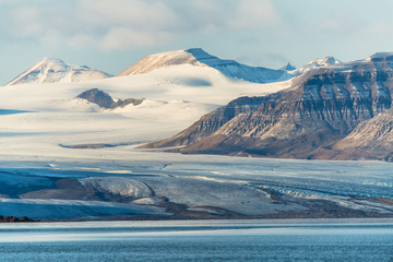 ein Gletscher vor schneebedeckten Bergen fließt ins Meer