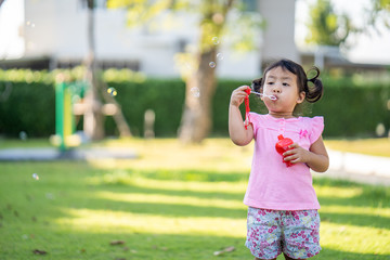 Cute little girl playing with bubbles in park. 