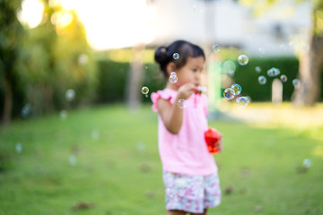 Cute little girl playing with bubbles in park. 