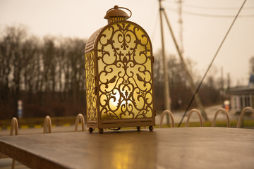 A fairy-tale lamp, a lantern, stands on the table of a street cafe. Comfort and warm yellow light.