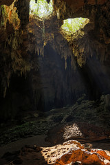 Beautiful cave with light rays come inside through holes into the rock.
