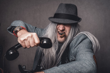Portrait skuril crazy Mann graue lange Haare und Hut mit altem Telefon und Zigarre Var.1