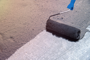 Worker applies bitumen mastic on the foundation