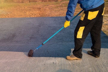 Worker applies bitumen mastic on the foundation