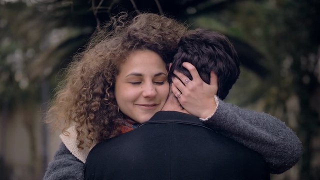 young woman embracing her boyfriend at the park and shushing  camera
