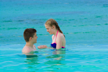 Fototapeta na wymiar Teenagers relaxing in infinity swimming pool in luxury hotel, Punta Cana, Dominican Republic. Summer vacation concept
