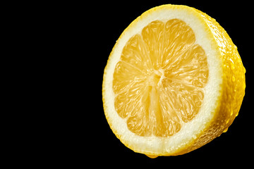 Closeup of half lemon with water droplets on black background