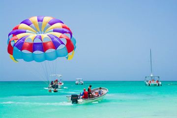 Boats and colorful parasail wing taking off from turquoise water of Sargasso Sea, Punta Cana, Dominican Republic - obrazy, fototapety, plakaty