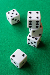 Top view of five dice, three stacked, on green mat, vertically with copy space