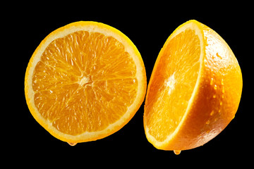  Fresh halves of orange with water droplets on black background