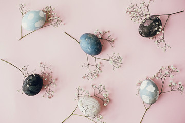 Stylish easter eggs and spring flowers composition on pink paper flat lay, space for text. Modern...
