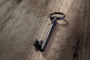 old rusty key from an old padlock lies on an old wooden background