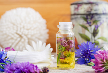 Fototapeta na wymiar Small bottle with wild flowers infusion (extract, tincture, essential oil). Aromatherapy, spa and herbal medicine concept. Copy space.
