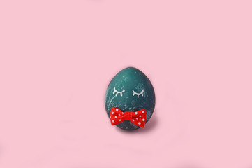 Creative Easter Funny blue egg with eyes and bow, on pink background. Natural dye of red cabbage. Easter holiday.Cope space. flat lay.Minimal concept.