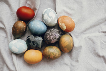 Stylish easter eggs on rustic table, flat lay. Natural dyed colorful easter eggs  on rural linen textile background. Space for text.