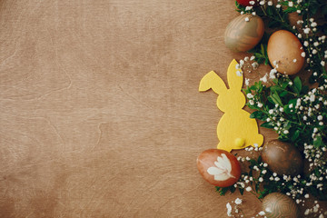Obraz na płótnie Canvas Happy Easter. Stylish easter eggs, yellow bunny, spring flowers on rustic wooden table flat lay, space for text. Natural dyed easter eggs and rabbit decorations on wood. Card mockup
