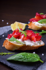 Trout Gravlax on the slices of white bread with ricotta topped with greenery on the stone platter. Nordic cuisine meal