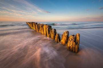 Baltic Sea. Wooden piles on the beach during sunset.