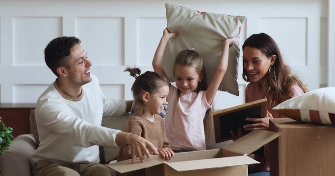 Excited family with kids unpacking boxes together on moving day