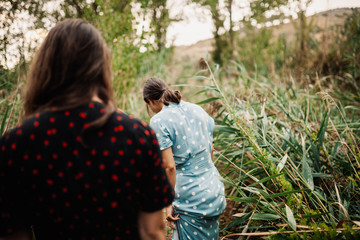 Back view of two young women walking through the field