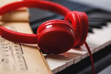 Sheet music and red headphones on the piano keys
