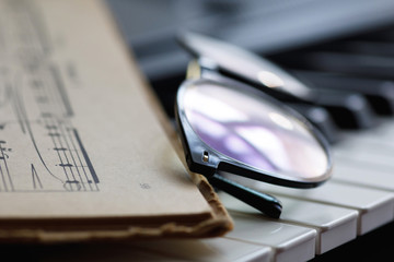Sheet music and eyeglasses on the piano keys