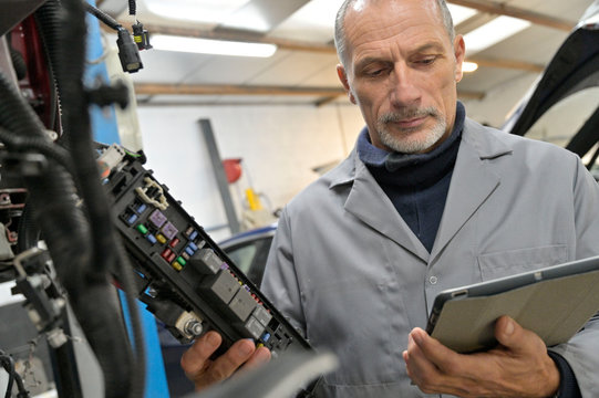 Engineering technician checking vehicle in workshop