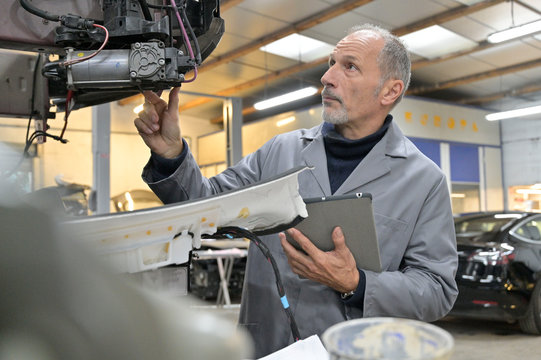 Engineering technician checking vehicle in workshop