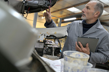 Engineering technician checking vehicle in workshop