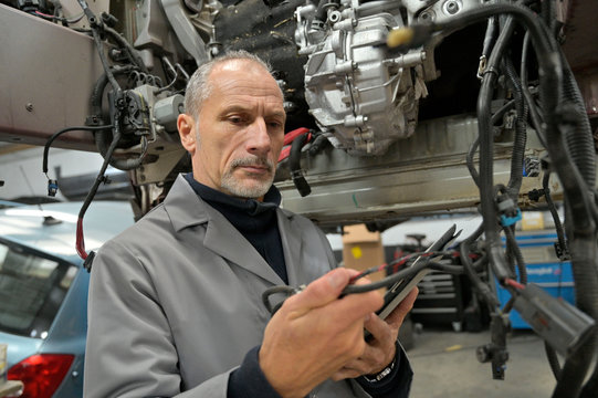 Engineering technician checking vehicle in workshop
