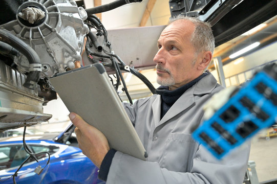 Engineering technician checking vehicle in workshop