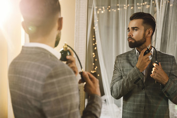 Handsome bearded man is using atomizer nozzle with perfume