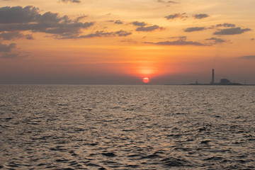 The red sun over the evening sea near the industrial area by the sea