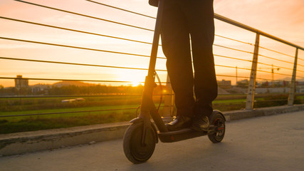 LOW ANGLE: Businessman rides an e-scooter to work on a sunny spring morning.
