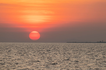 The red sun over the evening sea near the industrial area by the sea