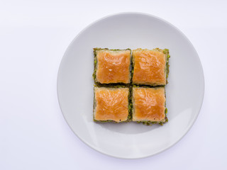 Sweet baklava with pistachio on a white isolated white service plate. Delicious baklava dessert in Antep style