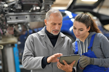 Apprentice with instructor using tablet in workshop