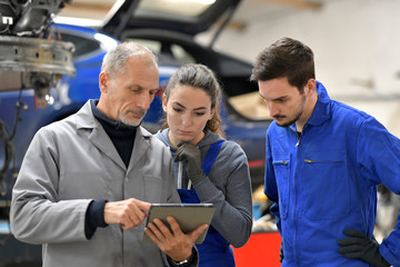 Apprentice with instructor using tablet in workshop