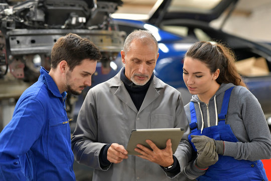 Apprentice with instructor using tablet in workshop