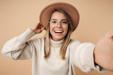 Portrait of cheerful young woman smiling and taking selfie photo