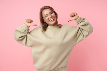 Portrait of young smiling woman winking and pointing thumbs herself