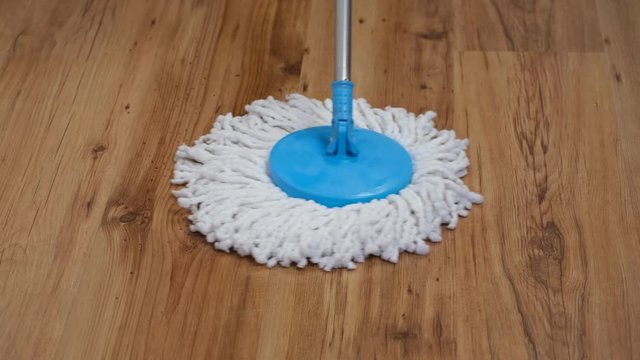 Front view of a flat wet mop wiping slowly left and right the parquet in the living room