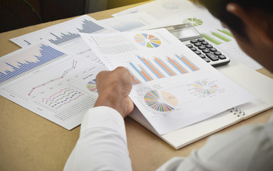 Obraz premium businessman analyzing financial graphs and charts report on desk in office.