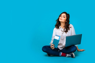 Naklejka premium Young woman sitting on the floor with laptop and passport buying tichets online