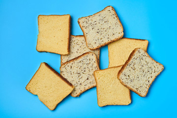 Heap of square pieces of bread with seeds and vanilla for toast lies on blue table on kitchen. Top view. Close-up