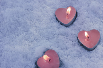 heart shaped candles on a background of snow