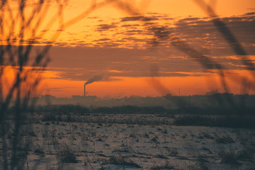 snow-covered field and the city on the horizon is beautifully lit by the rising sun