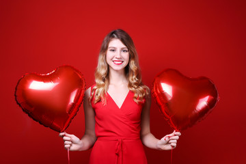 Portrait of young blonde woman posing with helium inflated air balloon. Happy valentine's day concept. Happy female with curled hair over colorful background. Close up, copy space for text.